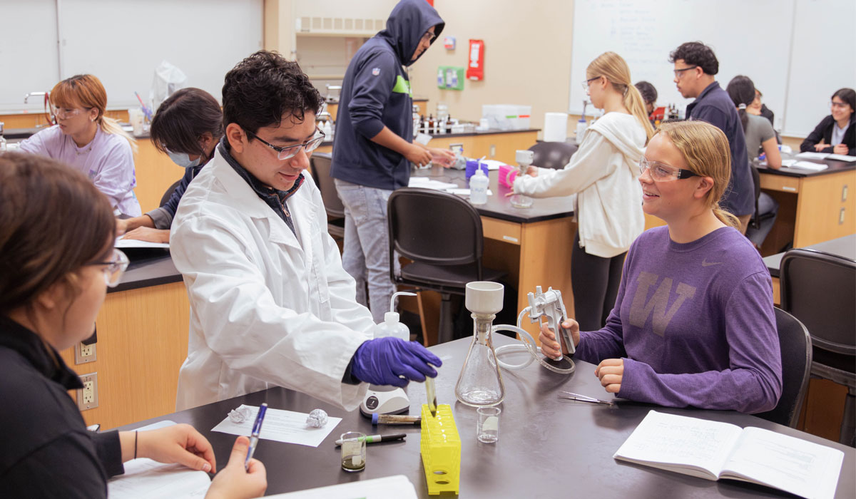 Biology teacher works with students during lab.