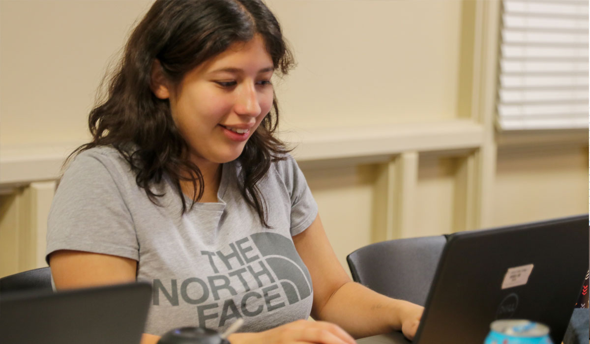 Student smiles while working on lap top.