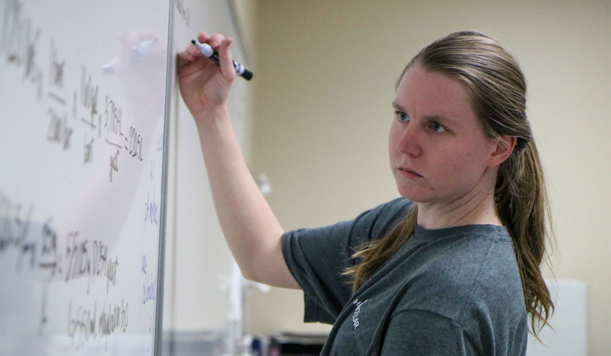 Student writes out problem on the white board. 