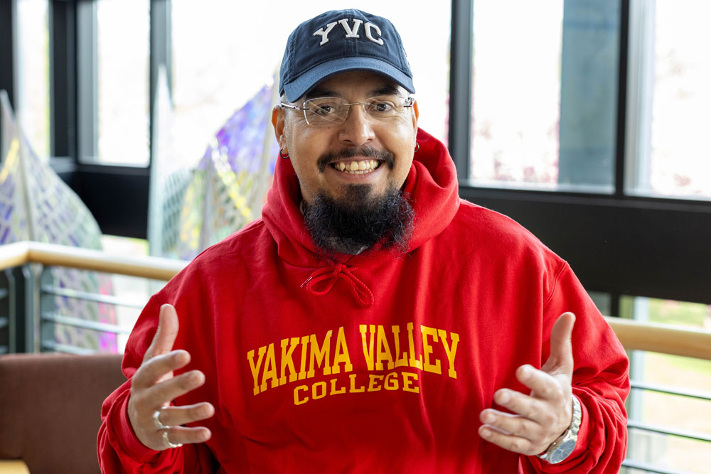 Carlos Hernandez poses for student story picture wearing YVC sweater and hat. 