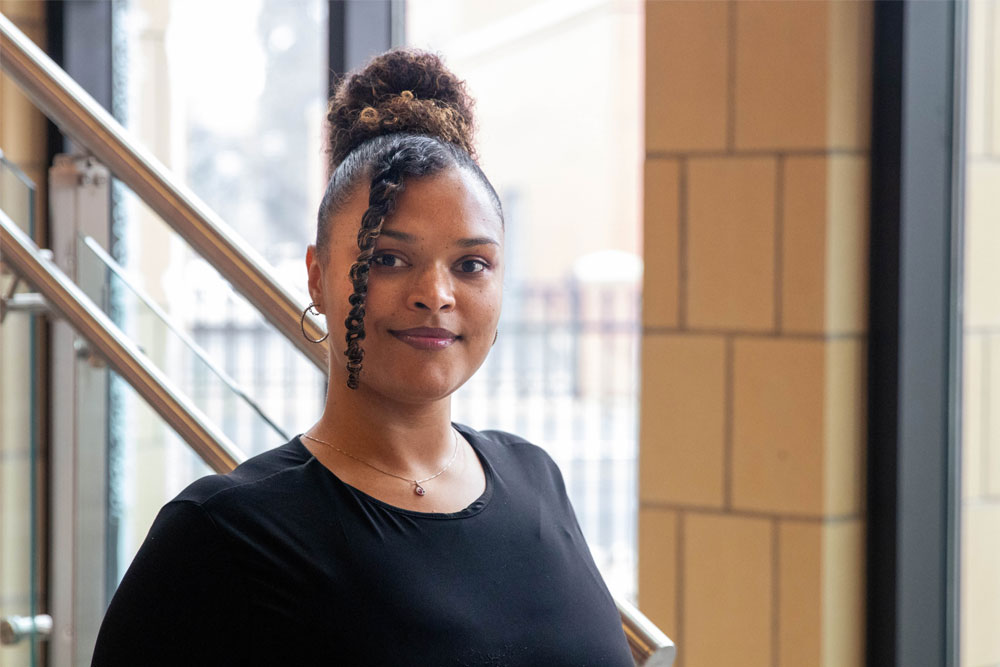 Carrisa Kimble poses for Student Story picture at the bottom of a YVC staircase. 