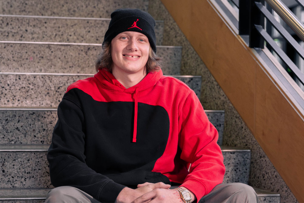 Jacob Mclam poses for Student Story picture while sitting on the stairs. 