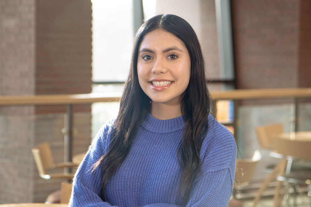 Yesenia Perez poses for student story picture inside an academic building. 