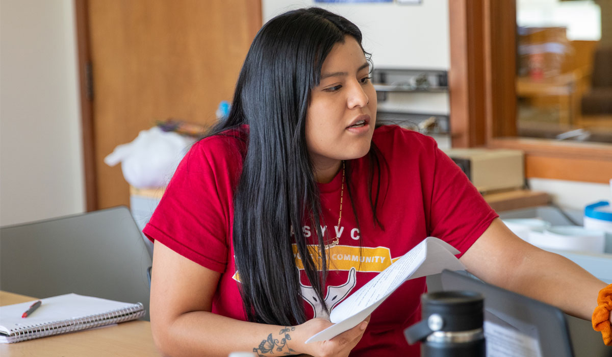 YVC student wearing red YVC shirt speaks during a meeting. 