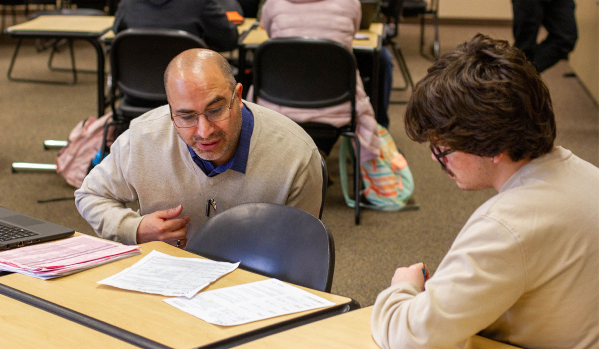 YVC instructor leans down to assist student during class. 