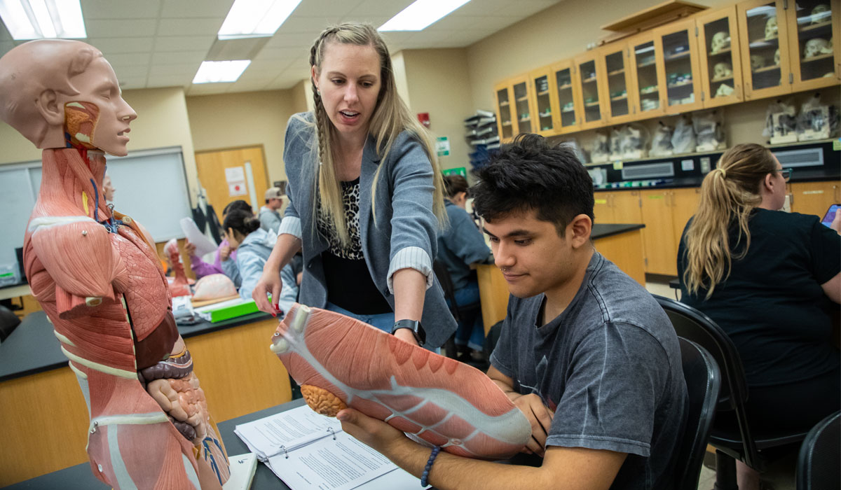 Instructor works with student during a healthcare class. 