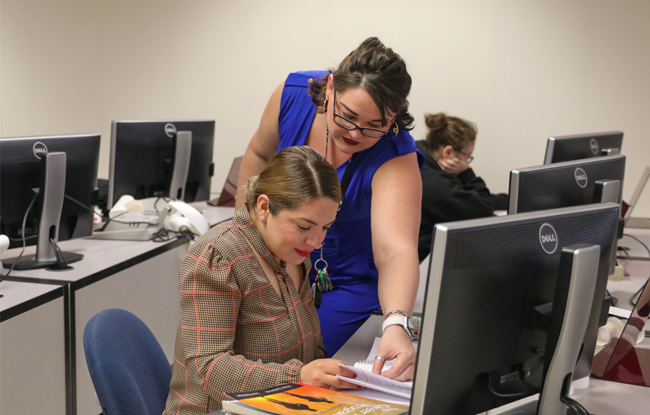 YVC  student sits at a computer while being instructed by a professor.