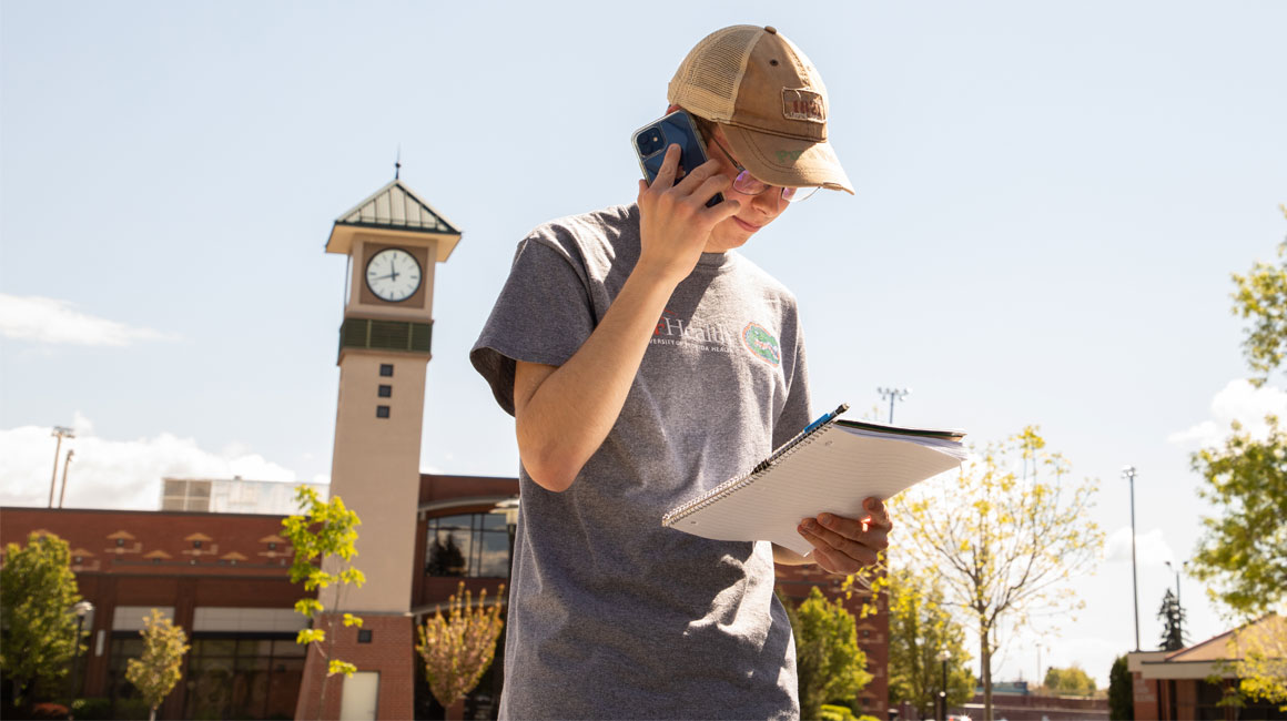 Student on his phone with YVC clocktower in the background. 