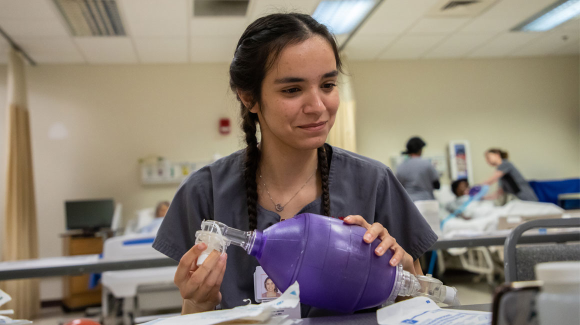 Nursing student learning on a medical instrument. 