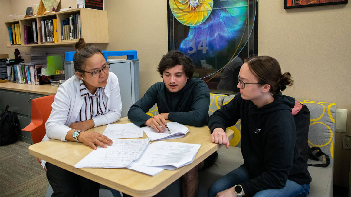 Staff member works with two students. 