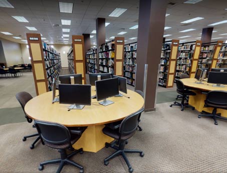 Raymon Library pictured with computers sitting on a group of round tables. 