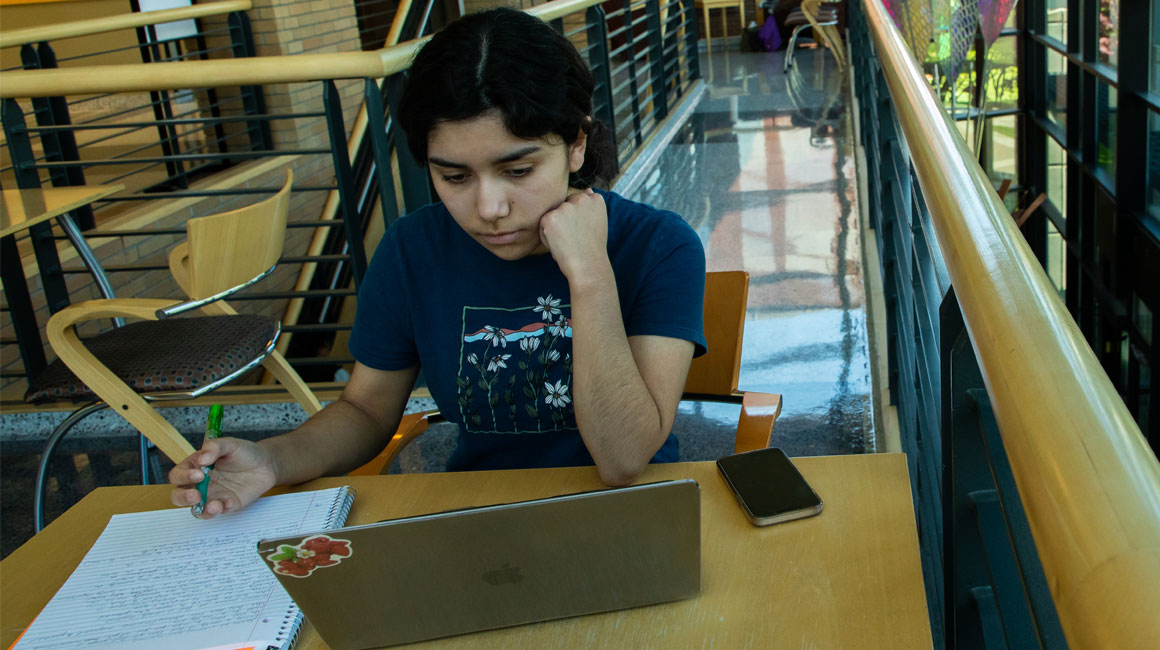 Student working on their lap top between classes in a YVC common area.