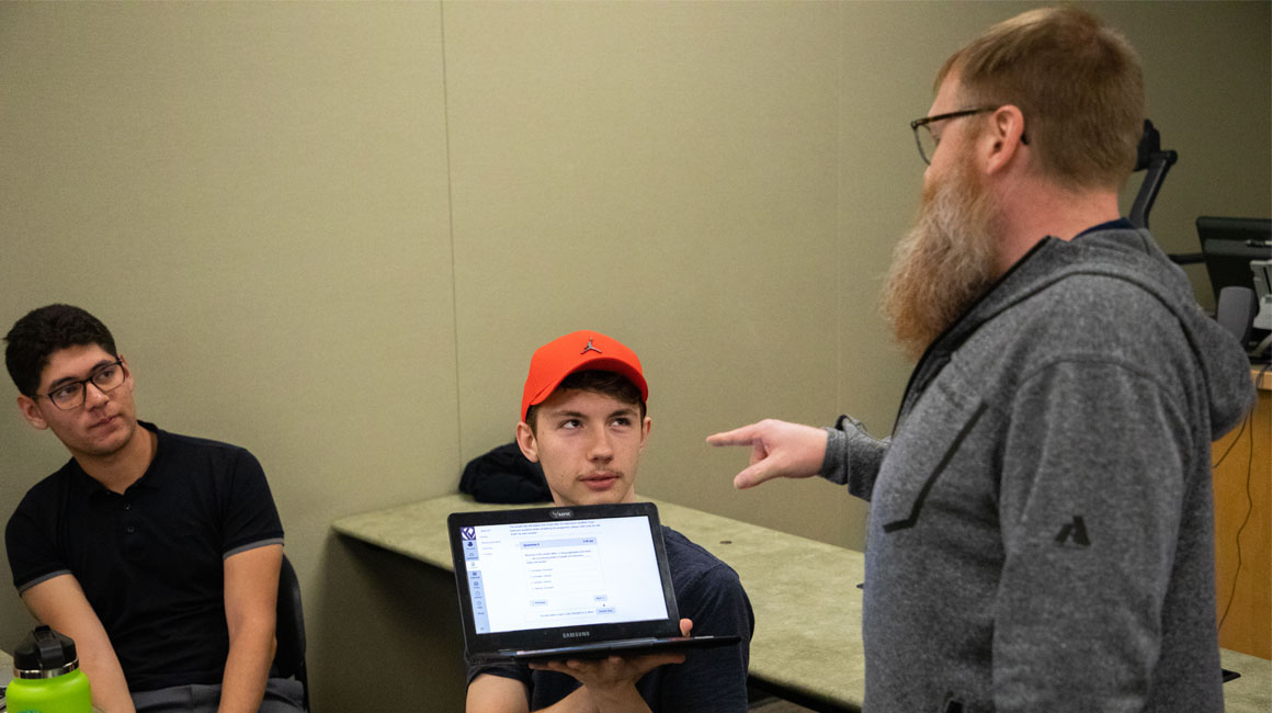 Student shows his instructor something on his lap top. 